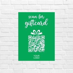 May include: A green sign with white text that says "scan for giftcard". Below the text is a white gift box graphic with a QR code. The bottom of the sign says "YOUR LOGO".