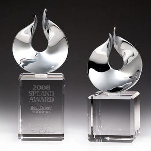 May include: Two crystal awards with a silver flame design. The award on the left has the text "2008 Spland Award Best Driver YOONHAK 2008.9.21 with Spland" engraved on the base.