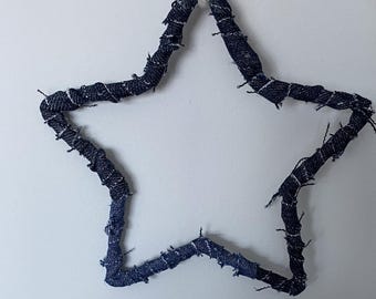 May include: A blue denim star-shaped ornament with frayed edges. The star is hanging from a white string.