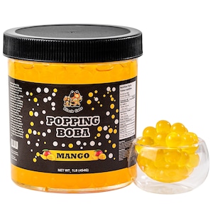 May include: A clear plastic jar of mango-flavoured popping boba with a black lid. The jar has a black label with the words "Popping Boba Mango" and a cartoon cat logo. A small glass bowl contains a serving of the mango boba. The jar contains 454g of product.