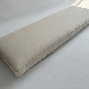 Puede incluir: Un coj&iacute;n rectangular para banco en color beige neutro. El coj&iacute;n tiene una apariencia a medida con un borde ribeteado. La tela tiene una textura sutil, que sugiere lino o un material similar. El coj&iacute;n est&aacute; dise&ntilde;ado para sentarse.