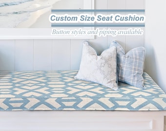 May include: A blue and white patterned seat cushion with a white wooden bench. The cushion is on a white wooden bench with a white wall behind it. The text "Custom Size Seat Cushion" and "Button styles and piping available" is on the wall above the bench.