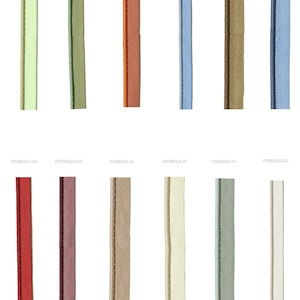 Puede incluir: Una colecci&oacute;n de cremalleras en varios colores, incluyendo verde, naranja, azul y marr&oacute;n. Cada cremallera se muestra verticalmente sobre un fondo blanco, mostrando los diferentes tonos y texturas de la cinta y los dientes de la cremallera.