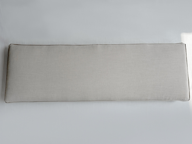 Puede incluir: Un coj&iacute;n rectangular gris claro para cabecero con ribete marr&oacute;n oscuro. El cabecero est&aacute; hecho de una tela texturizada y est&aacute; dise&ntilde;ado para colocarse contra una pared. El coj&iacute;n es largo y estrecho, adecuado para una cama.