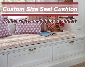 May include: A white window seat with a pink and white striped cushion. Two throw pillows with a pink and white floral pattern are on the seat. The text "Custom Size Seat Cushion" and "Button styles and piping available" is displayed above the seat.