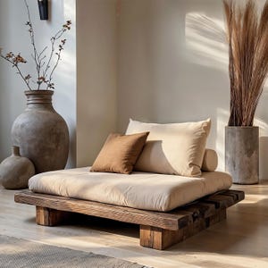 May include: A low, wooden platform bed with a beige mattress and pillows. A brown square pillow and a beige rectangular pillow are on the bed. A large, textured vase and a smaller vase are to the left. A tall concrete pot with dried plants is to the right.