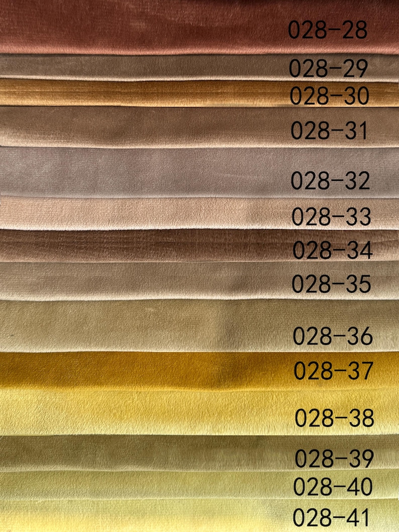 May include: A fabric swatch card featuring a variety of velvet upholstery samples in shades of brown, tan, and yellow. Each swatch is labeled with a unique number. The textures appear soft and plush, ideal for home decor projects.