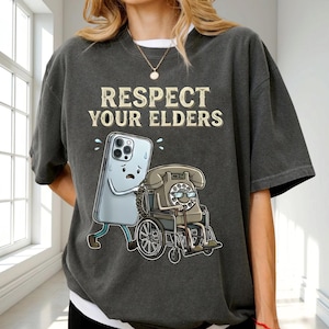 a person wearing a gray t-shirt with a graphic design depicting a phone and a wheelchair.