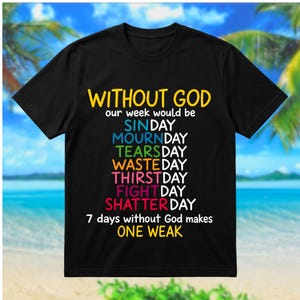 May include: A black short-sleeved t-shirt featuring the text: WITHOUT GOD our week would be SINDAY, MOURNDAY, TEARSDAY, WASTEDAY, THIRSTDAY, FIGHTDAY, SHATTERDAY. 7 days without God makes ONE WEAK. The text is printed in yellow, blue, green, orange, pink, and red.