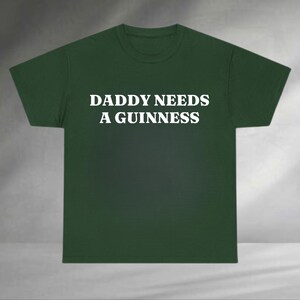 A green t-shirt with the text "DADDAY NEEDS A GUINNESS" printed on it.