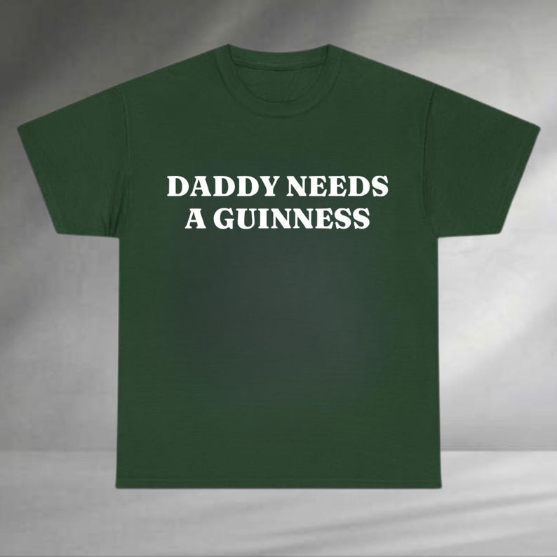 A green t-shirt with the text "DADDAY NEEDS A GUINNESS" printed on it.