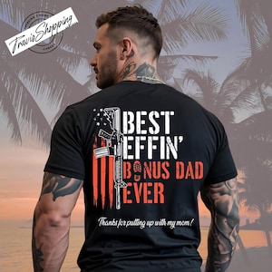 May include: Black t-shirt with the text "BEST EFFIN' BONUS DAD EVER" in white and orange, along with an illustration of a rifle and the American flag. The shirt also includes the phrase "Thanks for putting up with my mom!"