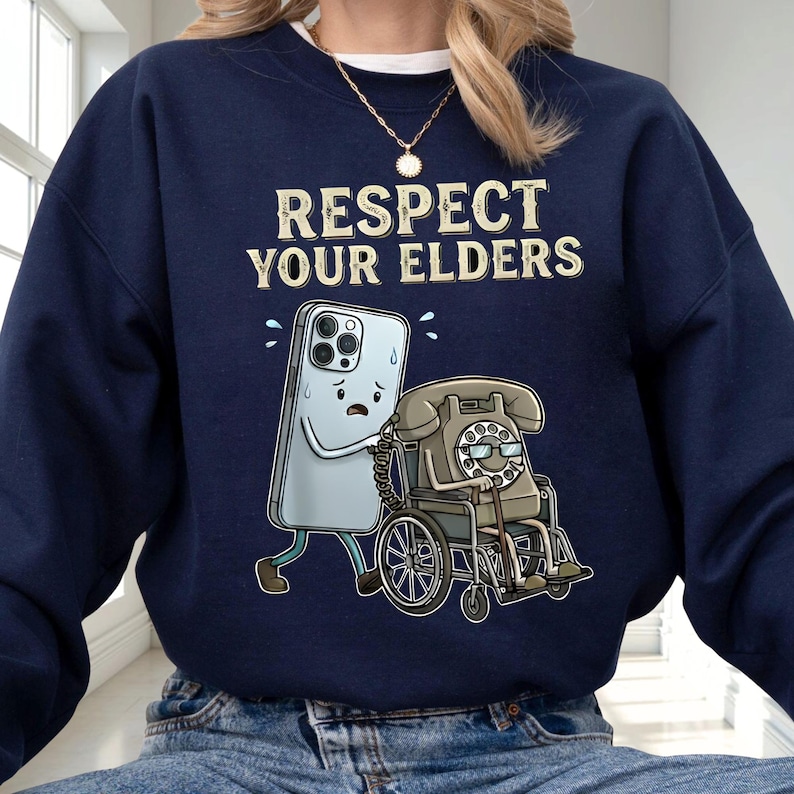 A person wearing a navy blue sweatshirt with a graphic design depicting a phone character with a wheelchair and the text "RESPECT YOUR ELDERS" printed on it.