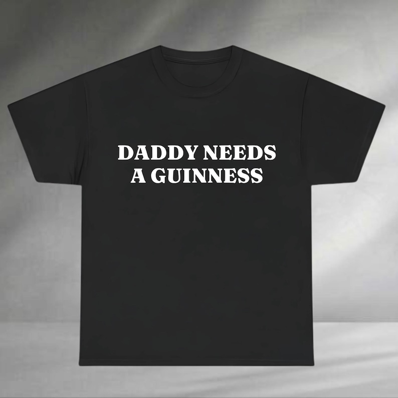 A black t-shirt with white text that says "DADMY NEEDS A GUINNESS".