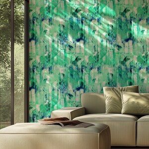 May include: A contemporary living room with a light beige sofa and ottoman. The wall is decorated with abstract green and blue patterned wallpaper. Sunlight streams through a large window, illuminating the room. The room has a modern design.