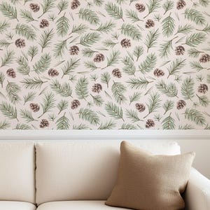 May include: A cream-colored sofa with a brown textured pillow. The wall behind the sofa is decorated with a repeating pattern of green pine needles and brown pine cones on a cream background.