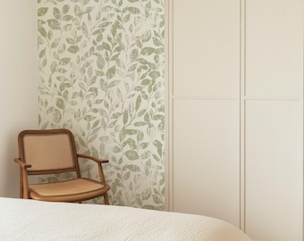 May include: A bedroom scene featuring a bed with a white textured comforter, a wooden chair with a woven seat, and a wardrobe. The wall is decorated with a green and white leaf pattern wallpaper, creating a natural and calming atmosphere.
