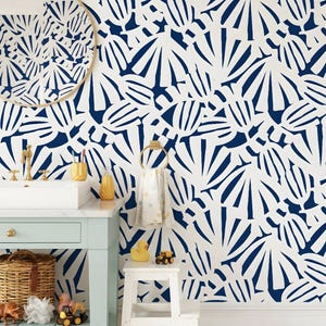 May include: A bathroom featuring a white sink, a pale blue vanity, and a wall adorned with a blue and white pattern. A circular mirror is above the sink. A towel rail holds a white towel. A small white stool holds a rubber duck and a toy truck.