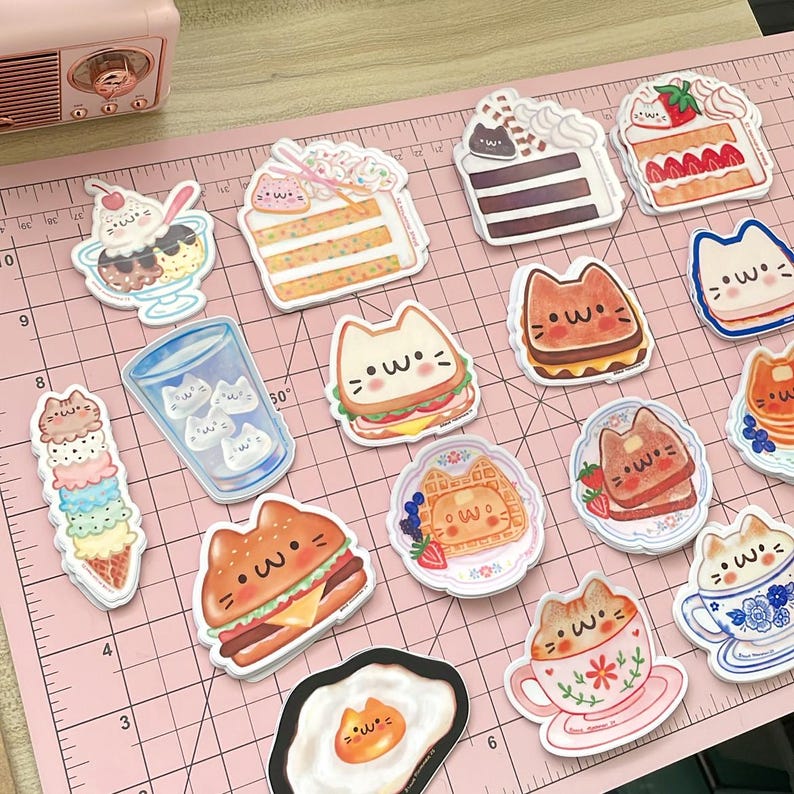 May include: A set of 14 colorful stickers featuring cute cartoon cats enjoying various foods and drinks. The stickers include a cat eating a sandwich, a cat drinking coffee, a cat eating a waffle, a cat eating a burger, a cat eating an egg, a cat eating a cake, a cat eating ice cream, a cat drinking a glass of water, and a cat eating a slice of cake. The stickers are perfect for adding a touch of whimsy to your laptop, water bottle, or planner.