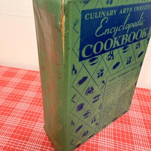 May include: A green hardcover Culinary Arts Institute Encyclopedic Cookbook with a blue diamond pattern featuring small food icons. The front cover displays the title and a Quick Reference Index. The spine shows signs of wear and paper separation.