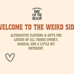 May include: A cream-colored graphic sign featuring the text RISE OF THE MOON with an eye icon, WELCOME TO THE WEIRD SIDE in orange, and ALTERNATIVE CLOTHING & GIFTS FOR LOVERS OF ALL THINGS SPOOKY, MAGICAL AND A LITTLE BIT DIFFERENT. A black heart icon.