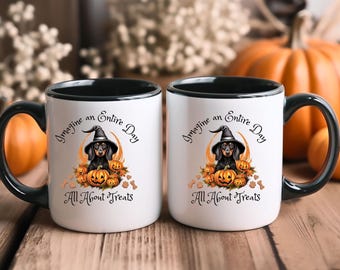 May include: Two white ceramic mugs with black handles and rims. Each mug features a dachshund wearing a witch hat, surrounded by pumpkins, with the text "Imagine an Entire Day All About Treats."