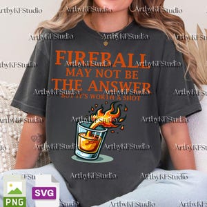 May include: Dark gray t-shirt with the text "Fireball may not be the answer but it's worth a shot" in orange. The shirt features a graphic of a shot glass with flames. The shirt is a casual wear item.