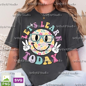May include: Dark gray t-shirt with a colorful graphic. The graphic features a smiley face wearing glasses, surrounded by the words "Let's Learn Today" in various colors and fonts. The smiley face has a floral pattern.