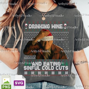 May include: Dark gray t-shirt with a festive design. The shirt features the text "DRINKING WINE" above an image of a man wearing a Santa hat, and the text "AND EATING SINFUL COLD CUTS" below. The design includes wine glasses and snowflake patterns.