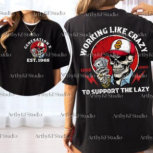 May include: Black t-shirt with a graphic featuring a skull wearing a cap and holding money. The front of the shirt says "GENERATION X EST. 1965". The back of the shirt says "WORKING LIKE CRAZY TO SUPPORT THE LAZY".