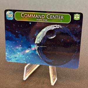 Könnte beinhalten: Eine Star Wars Trading Card mit einem dunkelblauen und schwarzen Bild des Todessterns mit einem blauen und violetten Nebel im Hintergrund. Die Karte hat einen grünen Rand mit dem Text "COMMAND CENTER" und "DEATH STAR" in Weiß. Die Karte hat die Nummer "30" in einem blauen Kreis oben links und ein grünes Symbol oben rechts.