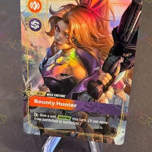 May include: A trading card featuring a female character with orange hair and a futuristic weapon. The card is titled "Bounty Hunter" and includes game text. The card is displayed on a clear plastic stand.
