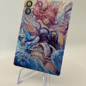 Puede incluir: Una tarjeta coleccionable con una ilustración vibrante de un personaje con cabello rosado y orejas de zorro. La tarjeta tiene el texto "AHRI Nine-Tailed Fox" e instrucciones del juego. La obra de arte está sobre un fondo azul y blanco.
