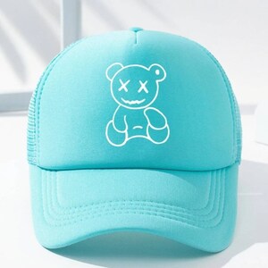 May include: A light blue trucker hat with a white outline of a bear with X's for eyes.