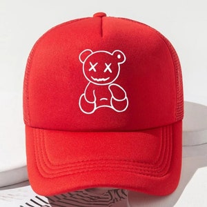 May include: Red mesh trucker hat with a white embroidered cartoon bear with X's for eyes.