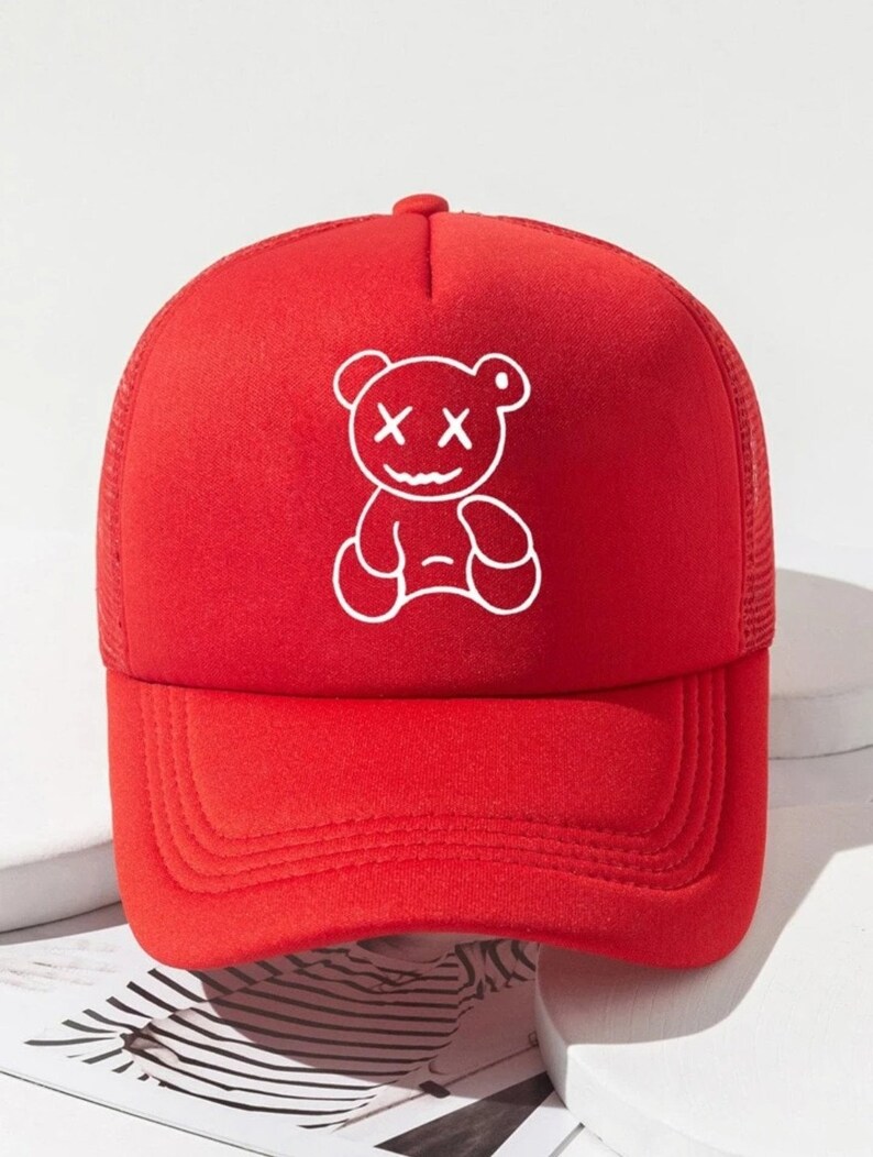 May include: Red mesh trucker hat with a white embroidered cartoon bear with X's for eyes.