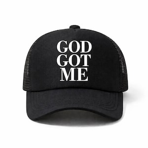Könnte beinhalten: Schwarze Trucker-Cap mit dem weißen Text "GOD GOT ME" auf der Vorderseite. Die Kappe hat einen gebogenen Schirm und eine Mesh-Rückseite. Ein modisches Accessoire für den Alltag.