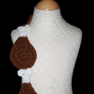 May include: A white crocheted mannequin with two brown crocheted chicken legs attached to the front.