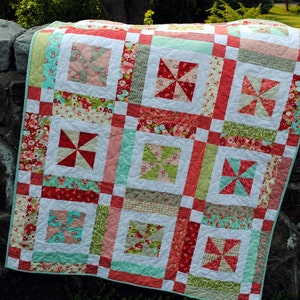 May include: A patchwork quilt with a white background and squares of red, pink, green, and blue fabric. The squares feature a variety of floral and geometric patterns.