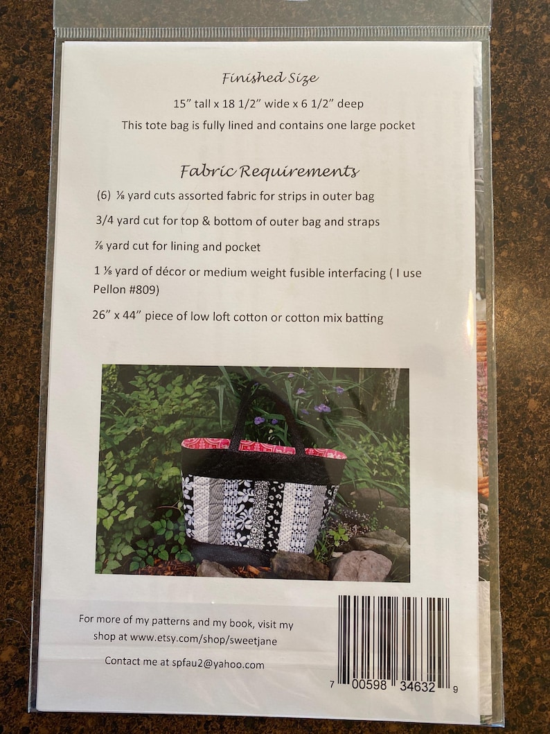 May include: A black and white tote bag with a floral pattern. The bag is 15 inches tall, 18.5 inches wide, and 6.5 inches deep. The bag is fully lined and has one large pocket. The fabric requirements for the bag are listed on the back of the card.