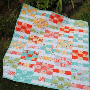 May include: A patchwork quilt with a variety of colorful fabrics in shades of red, orange, yellow, green, and blue. The quilt is made up of squares and rectangles, and the fabric patterns include floral prints, polka dots, and geometric designs.