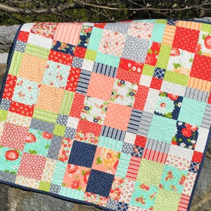 Peut inclure: Une courtepointe patchwork avec une variété de motifs floraux et géométriques dans des tons de rouge, orange, vert, bleu et blanc.