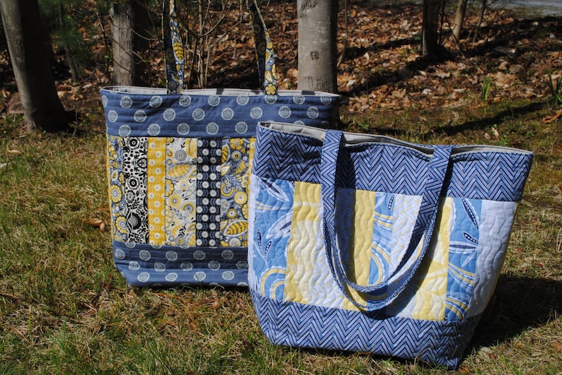 May include: Two quilted tote bags with blue and yellow fabric. The larger bag has a chevron pattern and the smaller bag has a patchwork design.