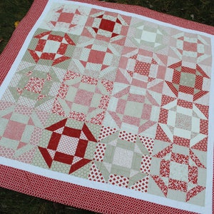 May include: A red and white quilt with a patchwork design. The quilt is made up of squares with different patterns, including stars, diamonds, and swirls. The quilt is edged with a red border.