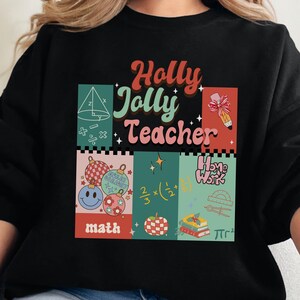 May include: Black sweatshirt with a Christmas-themed design that says "Holly Jolly Teacher" with illustrations of baubles, maths equations, and a pencil.