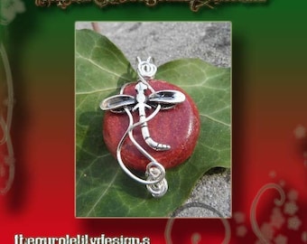 May include: A silver-toned dragonfly pendant with a red stone center. The dragonfly design is detailed, with curved lines and wing accents. The pendant rests on a green leaf, with the text "Captured dragonfly tutorial" and "thepurplelilydesigns" visible.