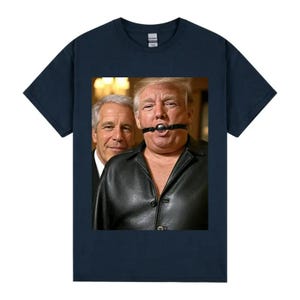 May include: A navy blue t-shirt with a graphic of two men. One is wearing a black leather jacket and a ball gag. The other man is wearing a suit. The image is centered on the shirt.