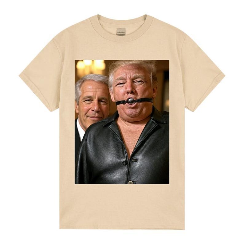May include: A beige t-shirt with a graphic of two men. One man is wearing a black leather jacket and a ball gag. The other man is wearing a suit and smiling. The t-shirt is made of a soft, comfortable material.