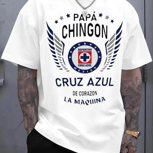 May include: White t-shirt featuring the text "PAPÁ CHINGON" above a circular emblem with a cross and the words "CRUZ AZUL MEXICO". The shirt also has the text "CRUZ AZUL DE CORAZON LA MAQUINA".