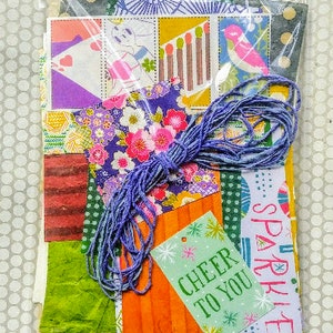 May include: A collection of colorful paper scraps and patterned fabric pieces, including a green tag with the text "Cheer to You Sparkle".